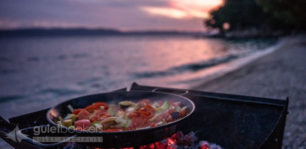 Dinner is served on the aft deck, with the illuminated coastline providing a magical backdrop.